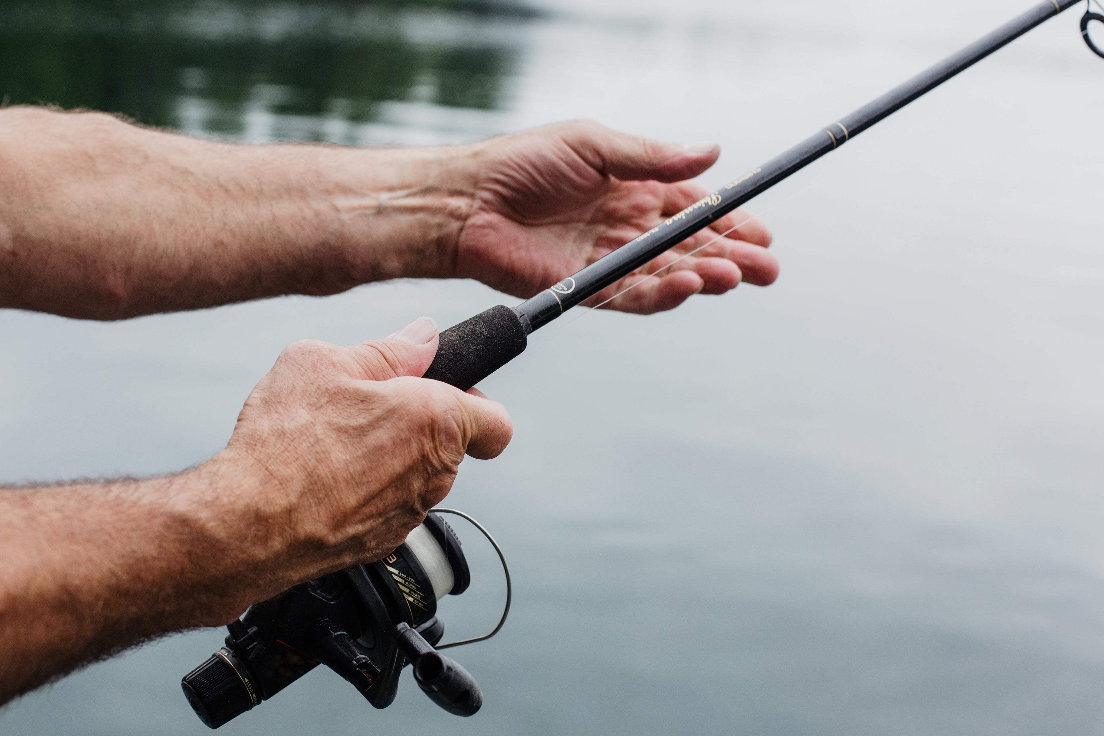 2 arms hold a fishing rod over still water, avon anglers