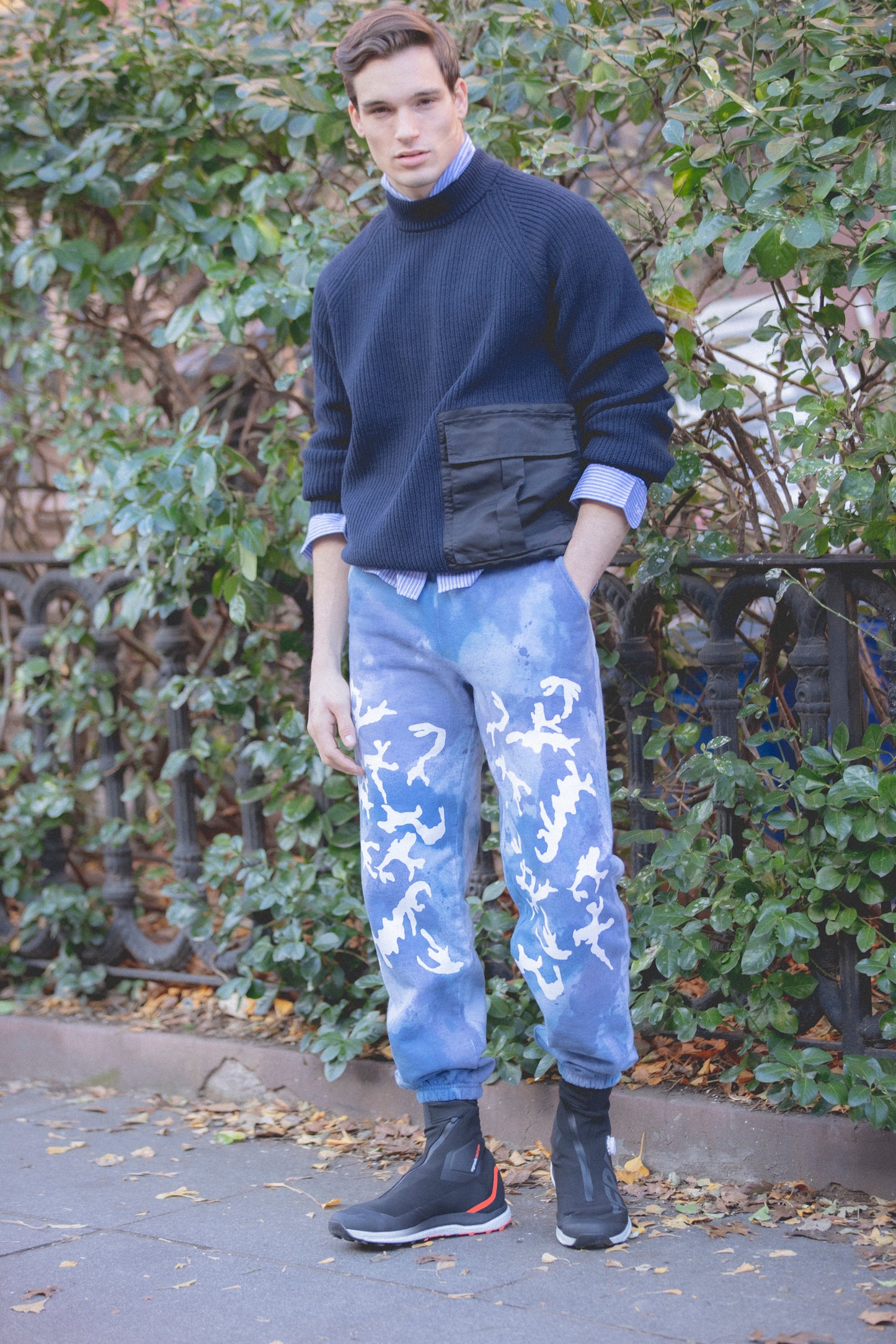 Model Mason McKenrick wearing Avon Anglers oversize navy sweater and hand painted and printed camo sweatpants on the street in brooklyn, designed by Patrik Rzepski.